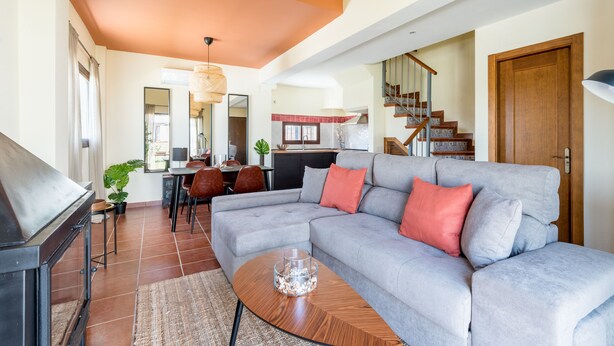 A modern living room with a grey sectional sofa, a wooden coffee table, and a staircase leading to an upper floor.