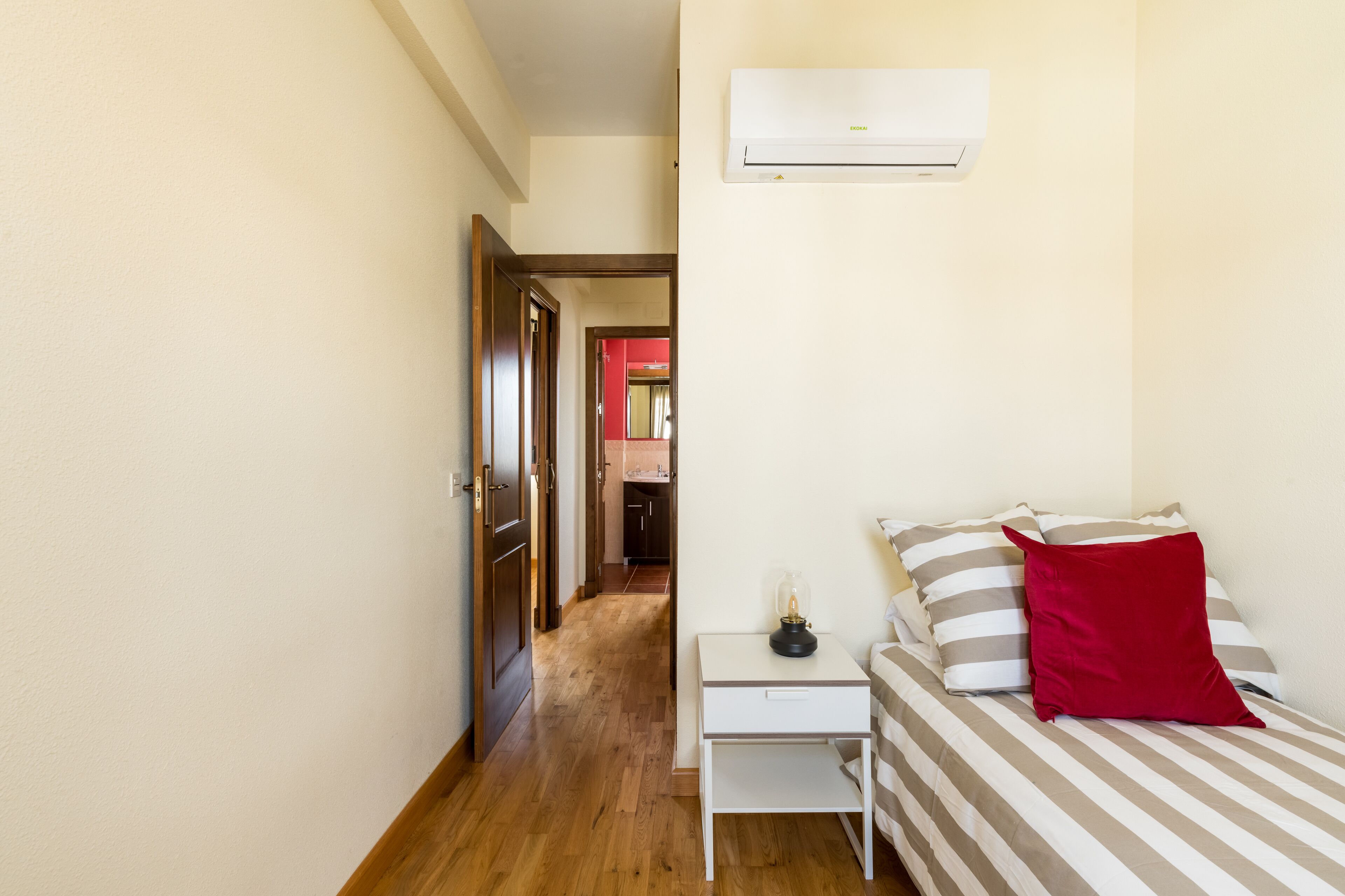 Une chambre à coucher comprenant un lit, une table de chevet et un appareil de climatisation.
