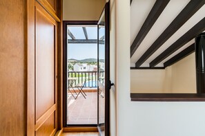 A wooden door leading to a balcony with a view of houses and a pool.
