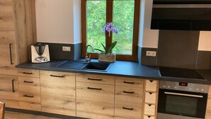 Ett modernt kök med träskåp, en inbyggd ugn och ett fönster med utsikt över grönområden.
