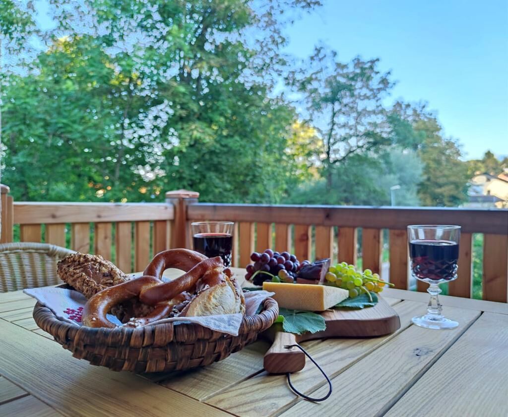 Ein Picknick mit einer Korb gefüllten Brezeln, Käse, Trauben und einer Weinflasche auf einem Holztisch.