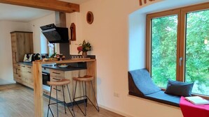 Ett modernt kök med träskåp, en inbyggd spis och en fönsterplats med en röd kudde.