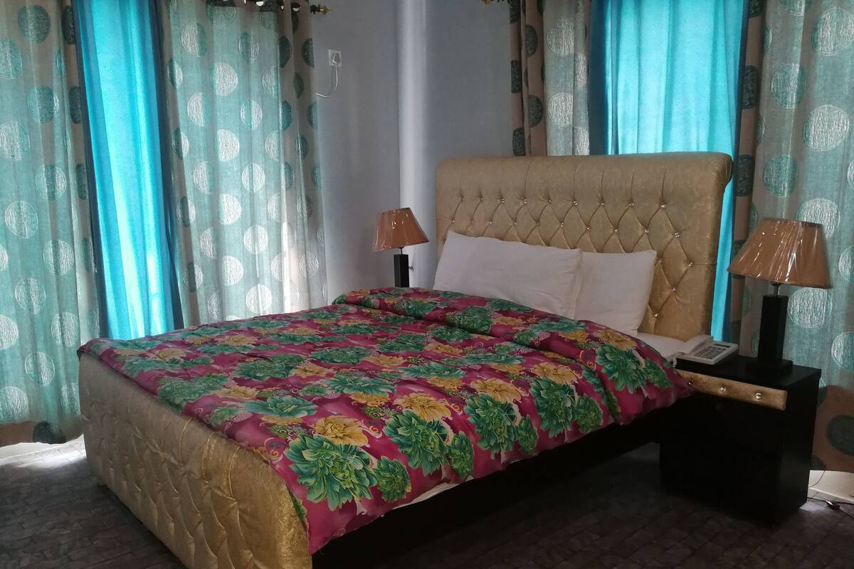 A bed with a floral bedspread, a tufted headboard, and two bedside lamps.