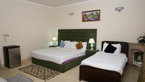 A hotel room with two beds, a small refrigerator, a heater, and a painting on the wall. - Rio Inn West (Mekhtar)