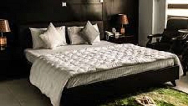 A bedroom with a large bed, dark walls, and a small rug. - Rio Inn West (Mekhtar)