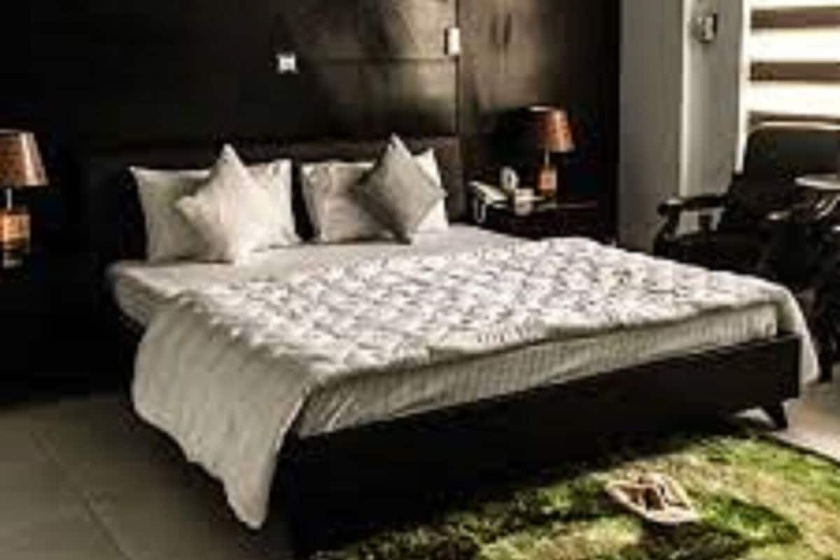 A bedroom with a large bed, dark walls, and a small rug.