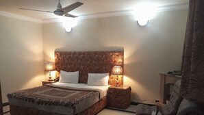 A bedroom with a large bed, two bedside lamps, a ceiling fan, and a nightstand with a lamp. - Rio Inn West (Mekhtar)