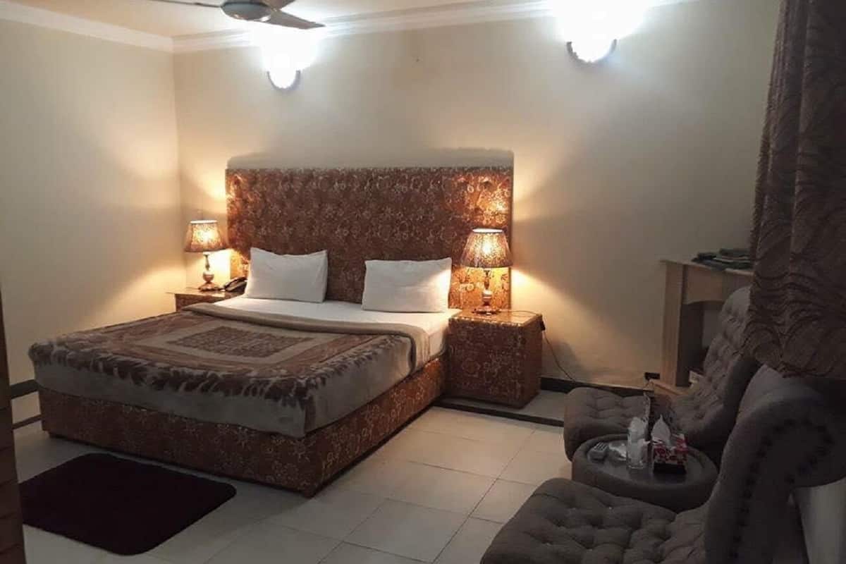 A bedroom with a large bed, two bedside lamps, a ceiling fan, and a nightstand with a lamp.