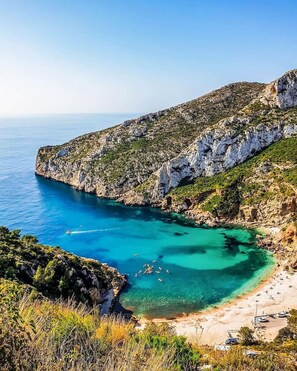 A coastal landscape with a rocky cliff, clear turquoise waters, and a sandy beach. - Villa near beach & town on foot (Xàbia)