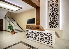Zona de recepción con escalera, televisor de pantalla plana y paneles decorativos.