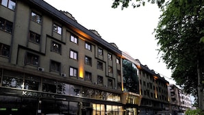 A multi-story building with a ground-floor commercial space, including a visible restaurant named "KARABAK" and a hotel named "TURKISH HOTEL." Several cars are parked in front, and the building has a modern architectural style with large windows. - Turkler Hotel (Trabzon)