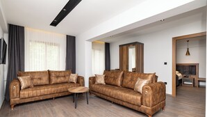 A modern living room with two brown leather sofas, a wooden coffee table, and a large mirror. - Turkler Hotel (Trabzon)