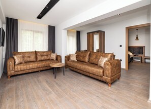 A modern living room with two brown leather sofas, a wooden coffee table, and a large mirror. - Turkler Hotel (Trabzon)