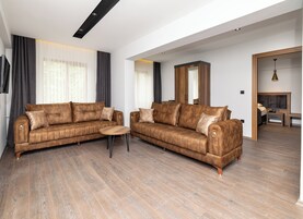 Una sala de estar moderna con dos sofás de cuero marrón, una mesa de centro de madera y un espejo grande.