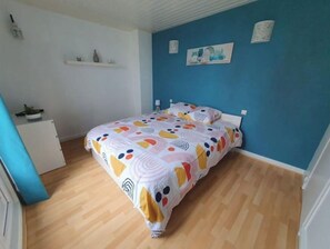 A bedroom with a bed, a dresser, and a blue wall with artwork. - L'Escapade Océane - downtown Le Havre (Le Havre)