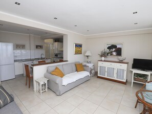 A compact living space with a kitchenette, a sofa, a TV, and a dining area.