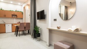 A modern kitchen with wooden cabinets, a dining area with chairs, a TV mounted on the wall, and a mirror.