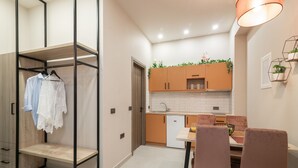 A compact kitchen with a dining area, a built-in wardrobe, and a pendant light.