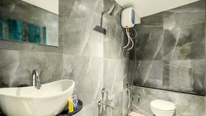 Un baño moderno con un lavamanos blanco, un cabezal de ducha manual y un inodoro.