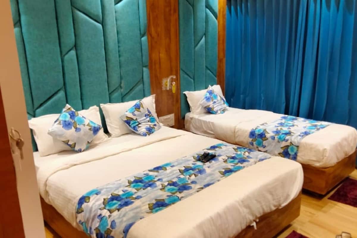 Habitación de hotel con dos camas, cada una con ropa de cama floral y almohadas a juego.