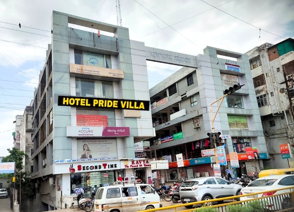 A multi-story building with various commercial establishments on the ground floor, including a dental clinic, a bank, and a pharmacy.