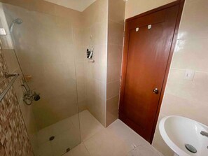 Ein Badezimmer mit Dusche, einer Holztür und einem weißen Waschbecken.