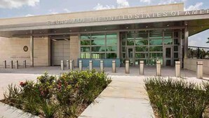The exterior of the United States Embassy building with a clear entrance, a large glass facade, and a landscaped area with plants in front. - Casa Durazno - Beautiful 3 Bed in Santo Domingo (Los Alcarrizos)
