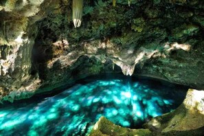 Eine natürliche Höhle mit einem Pool von klarem Wasser, der das Licht reflektiert.
