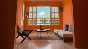 A spacious room with a large window, a sofa, a chair, and a small table. - Casa Durazno - Beautiful 3 Bed in Santo Domingo (Los Alcarrizos)