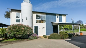 A two-story house with a cylindrical water tank, a covered porch, and a well-maintained garden.