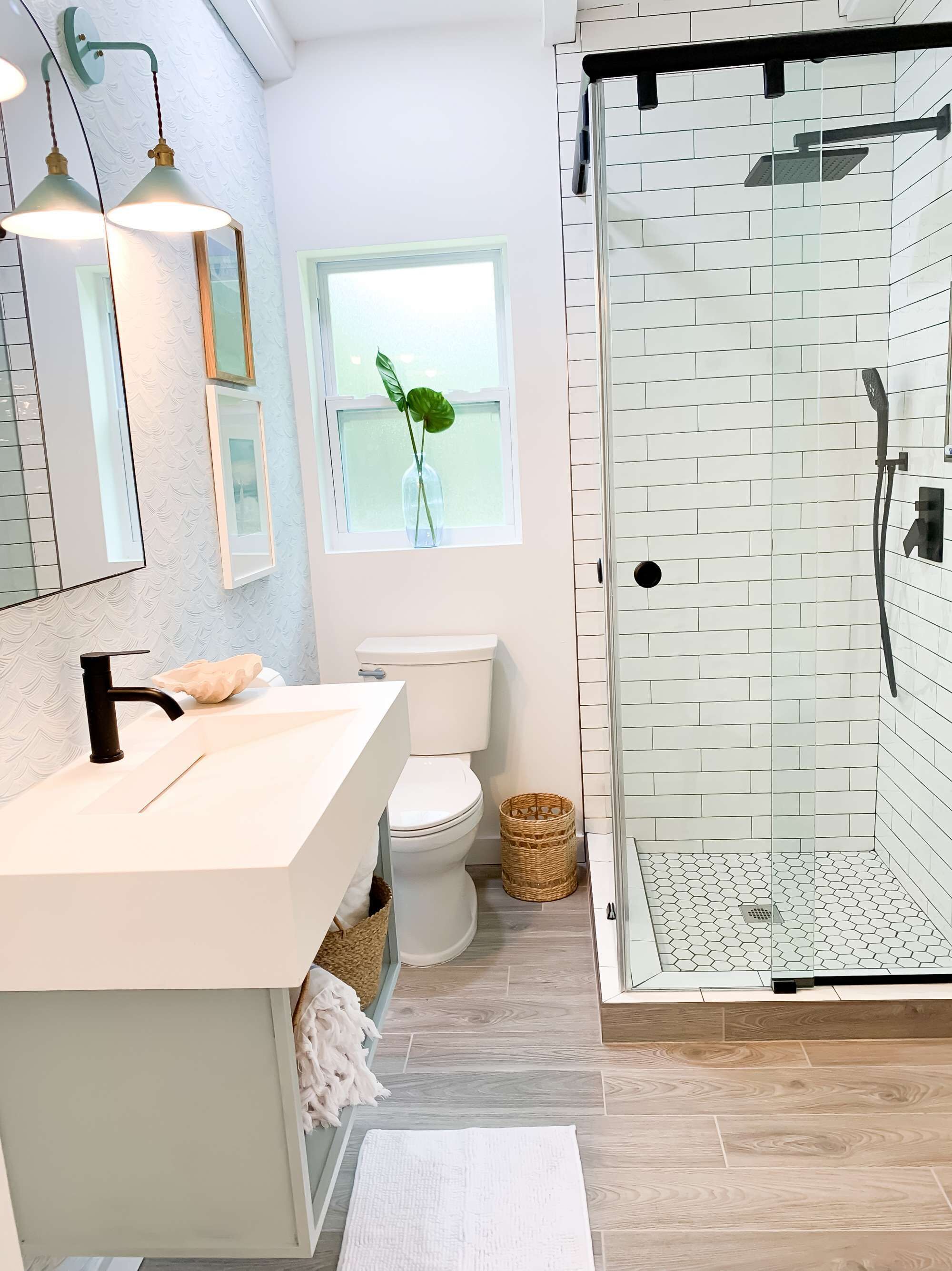 A modern bathroom with a white sink, toilet, and shower area.