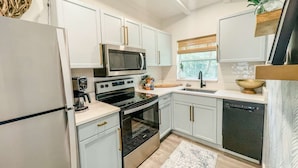 A modern kitchen with white cabinets, a built-in microwave, a stove, and a dishwasher.