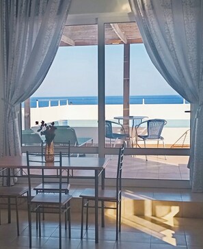A room with a view of the sea, a dining table, chairs, and a vase with flowers. - Exquisite Retreat For Two (Rhodes)
