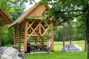 Une cabane en bois avec un coin repas, de gros rochers et un champ d’herbe.