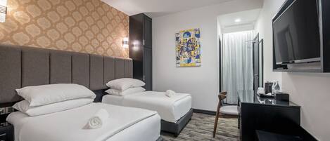 A hotel room with two beds, a flat-screen TV, a desk, and a patterned wall.