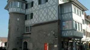 A multi-story building with a prominent tower section, large windows, and a stone base.