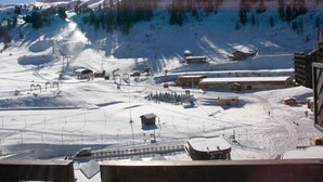 Une station de ski enneigée, avec des remontées mécaniques, des bâtiments et une montagne en toile de fond.