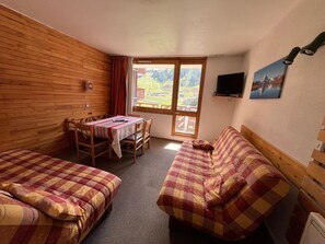 A room with two beds, a dining table, and a TV.