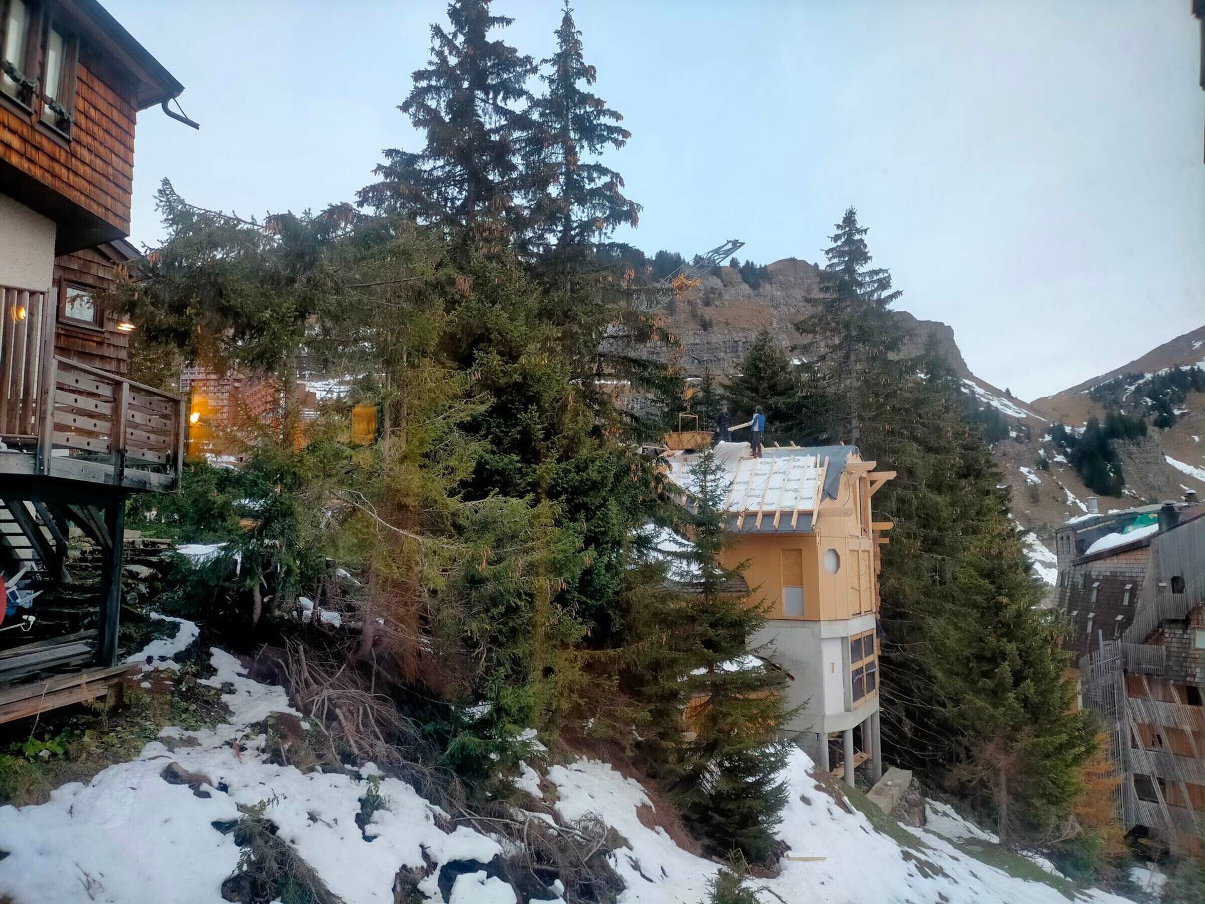 A mountainous area with a wooden building and a modern structure with a sloped roof.