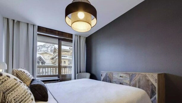 Een moderne slaapkamer met een groot bed, uitzicht op gebouwen en een bijzonder houten hoofdeinde.