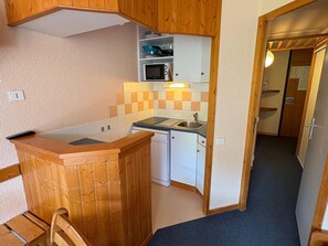 A compact kitchen with wooden cabinets, a microwave, and a sink.