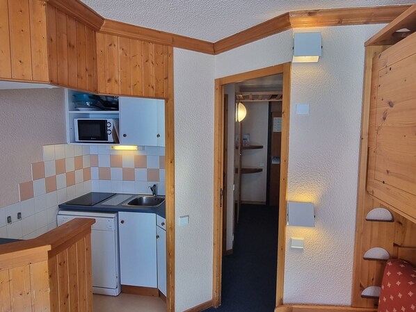 A compact kitchen with wooden cabinets, a microwave, and a dishwasher.