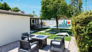 Um pátio externo com mobiliário de vime, uma lareira e uma área de piscina.