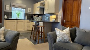 A modern kitchen with wooden cabinets, a central island with stools, and a dining table.