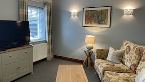 A living room with a flat-screen TV, a sofa, a coffee table, and a lamp. - Milecastle Inn on Hadrian's Wall Near Haltwhistle (Haltwhistle)