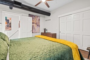 Ein Schlafzimmer mit einem Bett, einem Deckenventilator, einem Kleiderschrank und einer Tür.