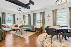 A modern living room with a sofa, chairs, a coffee table, and a dining table with chairs. - Belvedere Flats - 2 units + Walkable to Westport! (Kansas City)