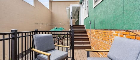 Una terrazza esterna con due poltrone grigie imbottite e un tavolo di legno.