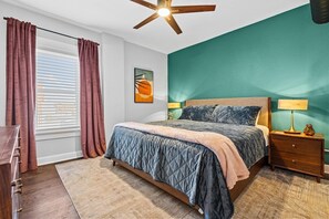 A bedroom with a bed, a nightstand, a lamp, a ceiling fan, and a window with curtains. - Belvedere 1 | Modern 3-Bed Flat in Westport (Kansas City)
