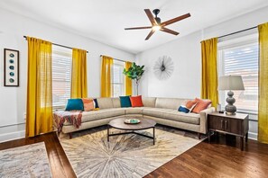 A living room with a sectional sofa, a coffee table, a floor lamp, and a ceiling fan. - Belvedere 1 | Modern 3-Bed Flat in Westport (Kansas City)